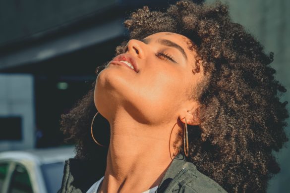 Gesunde Augen: Dunkelhäutige Frau hält Gesicht in die Sonne mit geschlossen Augen - Gesunde Augen im Sommer